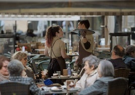 Dos camareros, que forman parte de uno de los sectores que se beneficiarán del cambio, atienden una terraza.