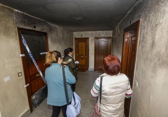 Alicia, María Luisa y Paula charlan en el rellano de su escalera, junto a la vivienda precintada donde se desató el incendio.