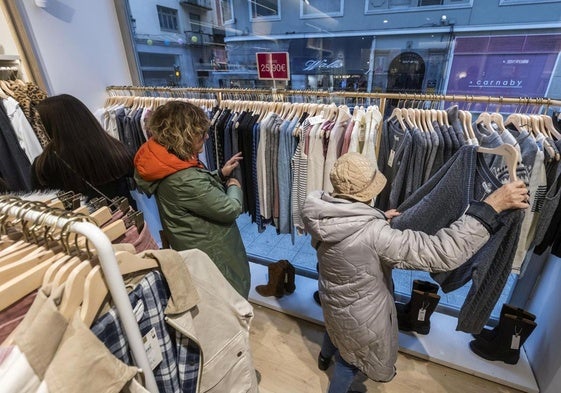 Tres mujeres miran la ropa expuesta en una tienda del centro de Santander.