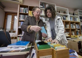 Asun Arabaolaza recoge algunos libros junto a la vicepresidenta de la asociación de vecinos, Virginia Pérez.