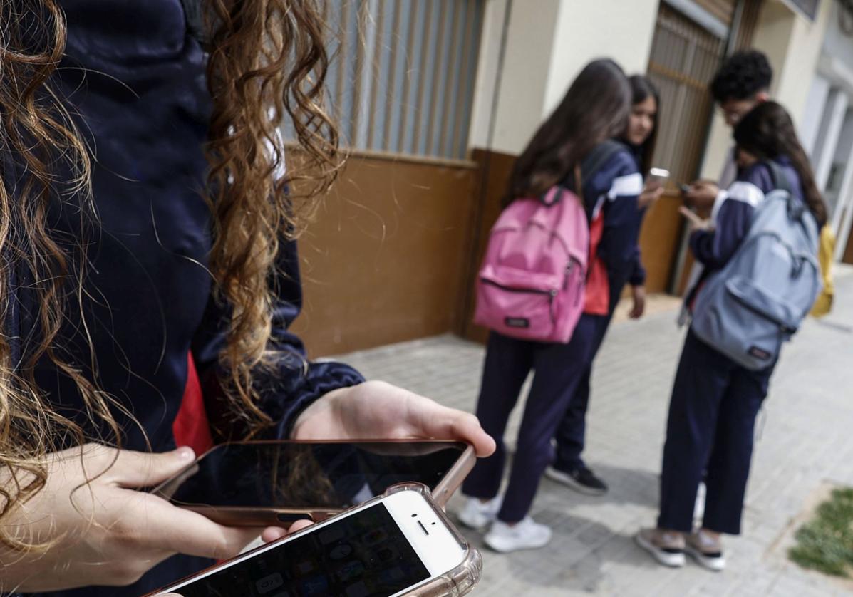 Varios estudiantes manejan sus teléfonos móviles, una escena muy difìcil de ver hoy en los centros educativos de Cantabria.