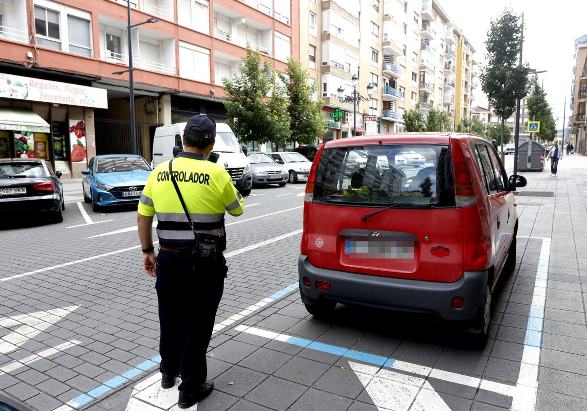 Un controlador toma los datos de un vehículoaparcado en una plaza ERA, en Torrelavega.