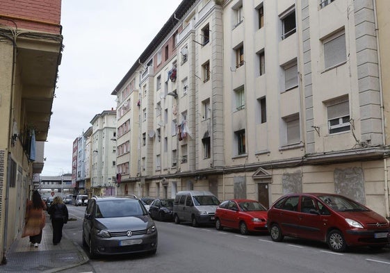 Vecinas caminan junto al número 9 de la calle Marqueses de Valdecilla y Pelayo, en La Inmobiliaria (Torrelavega).