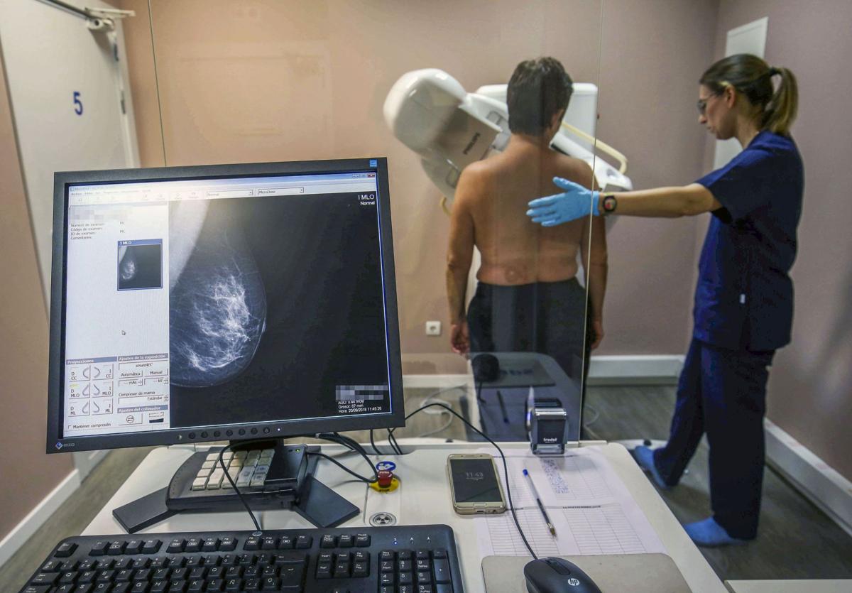 Una paciente se coloca en posición, con ayuda de una técnico de radiodiagnóstico, para realizarse una mamografía.