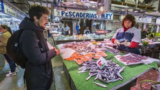 Un joven comprando bocartes en una pescadería del Mercado de la Esperanza.