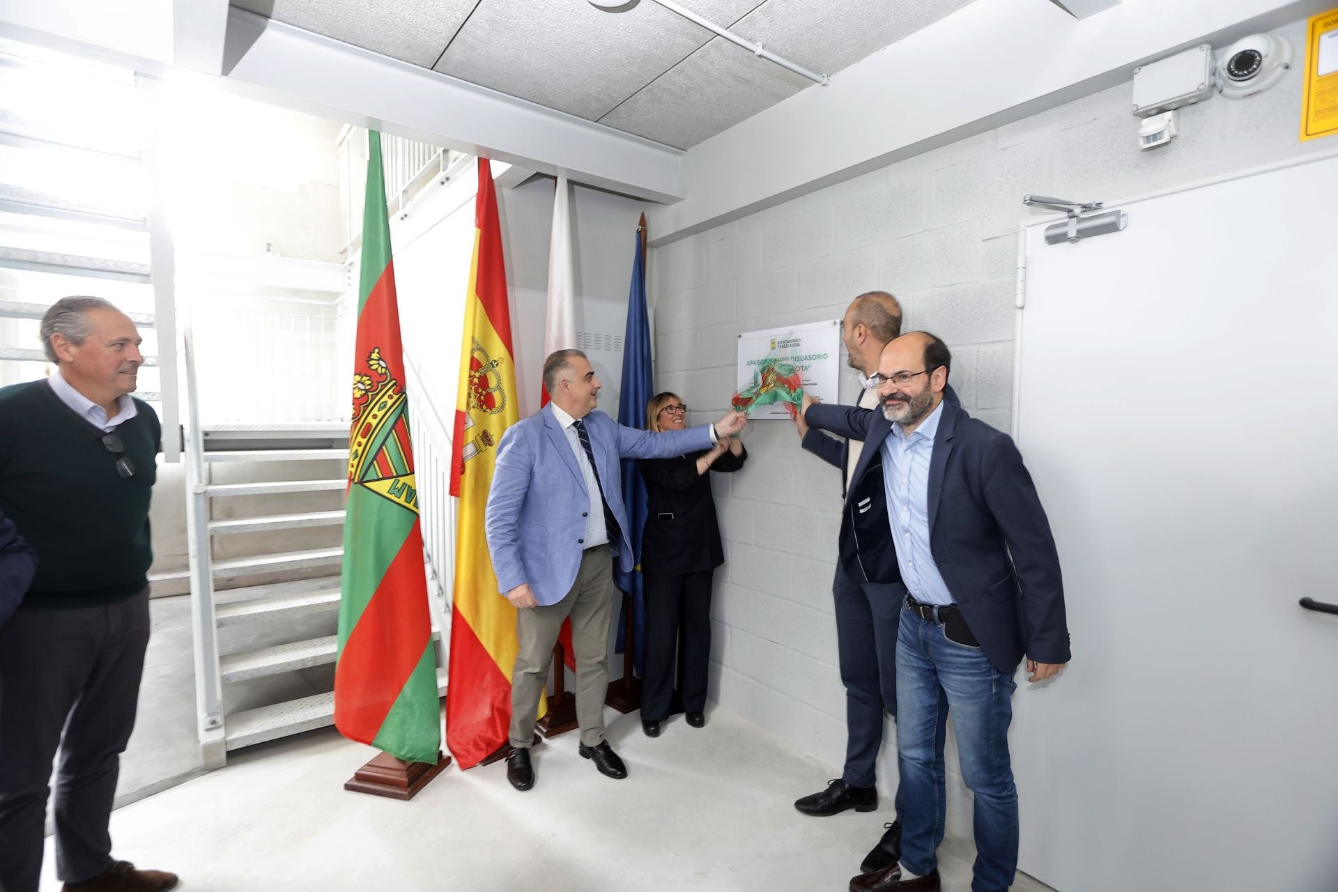 Autoridades municipales, regionales y nacionales destapan la placa del aparcamiento, en la entrada peatonal del edificio, este viernes, en Torrelavega. 