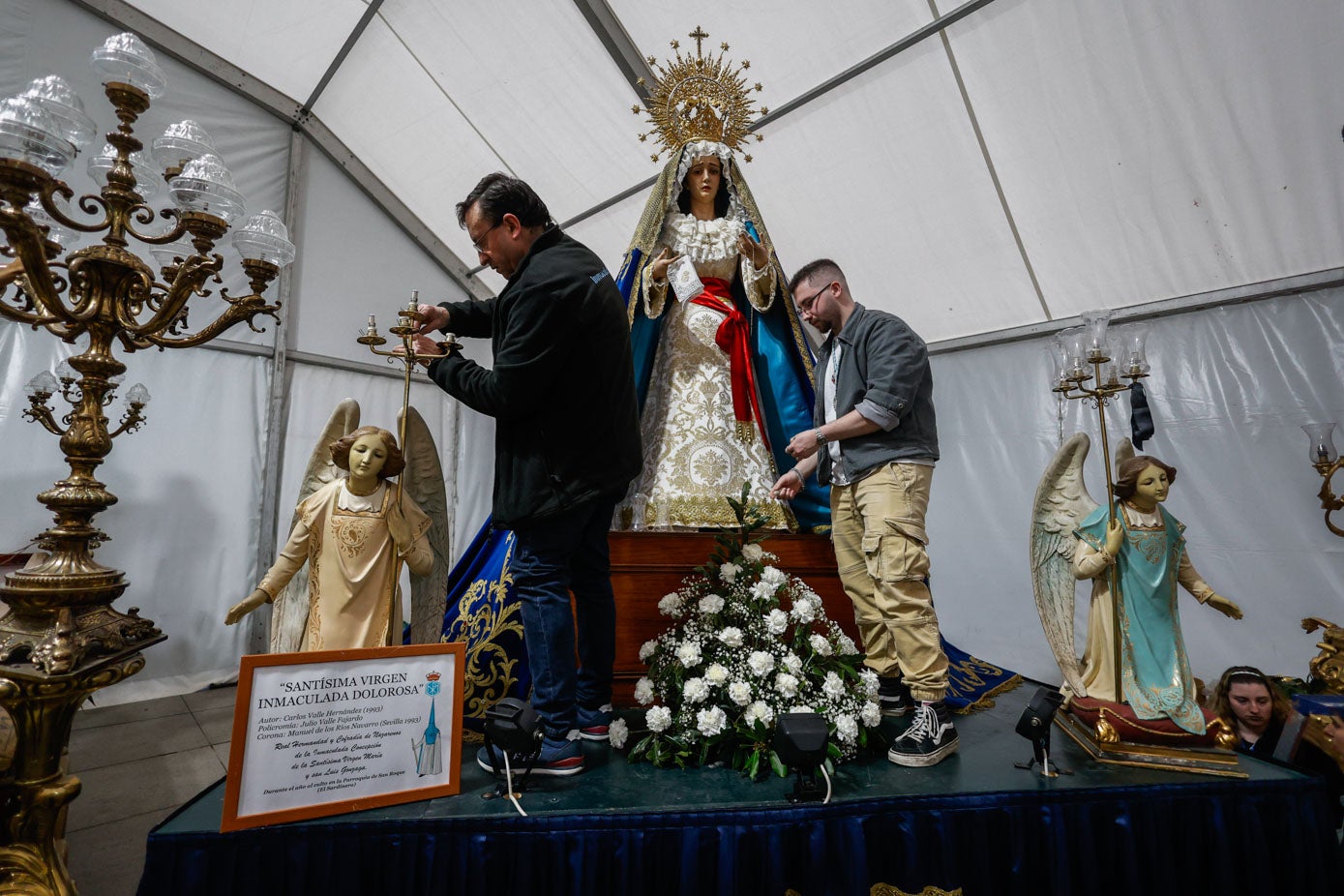 Dos cofrades trabajan con la imagen de la Inmaculada Dolorosa.