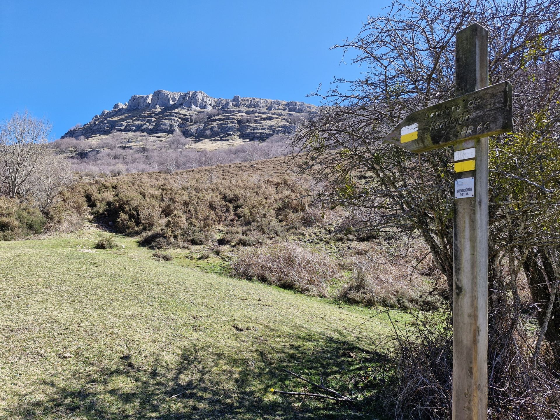 Otra señal, dejando a la izquierda una cabaña, indica que hay que seguir el camino entre escajos y escobales que va también por la izquierda.