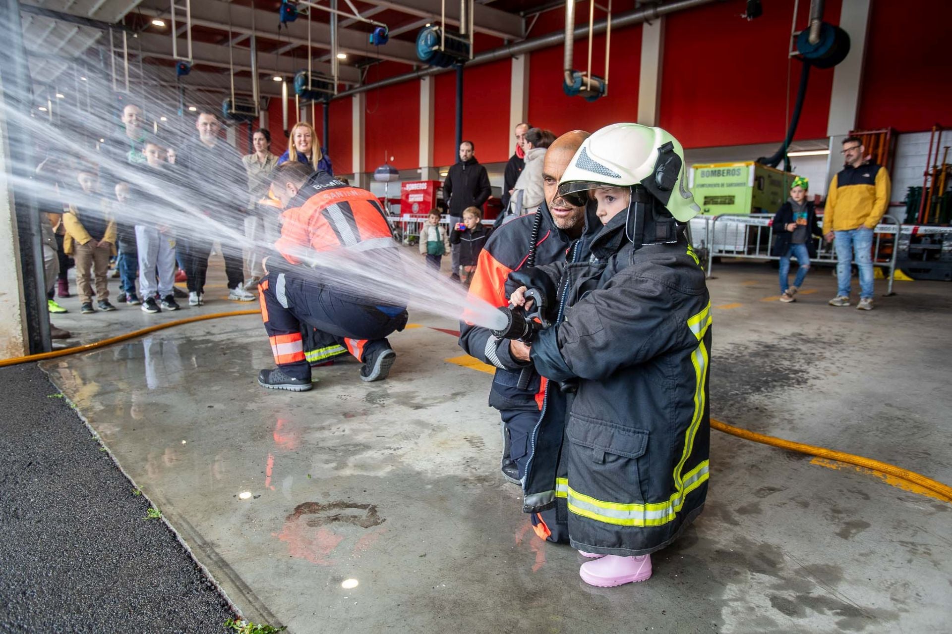 Una niña, este domingo, practica con la lanza que utilizan los bomberos de Santander, durante la jornada de puertas abiertas en Ojaiz.