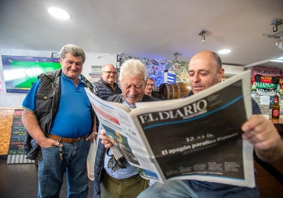 Una cuadrilla lee el periódico en el restaurante La Leña de Santander.