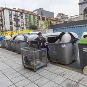 Un empleado desecha los residuos del negocio donde trabaja en un contenedor de resto.