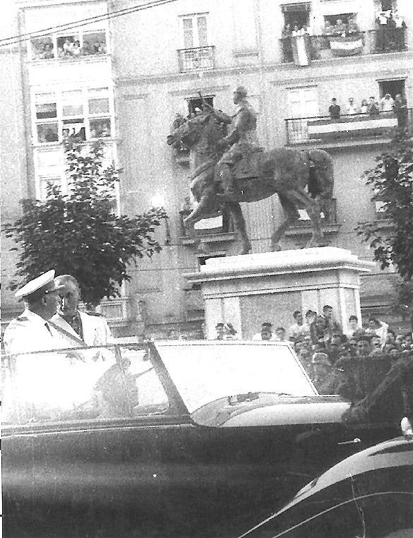 El dictador pasando en coche ante su estatua ecuestre.