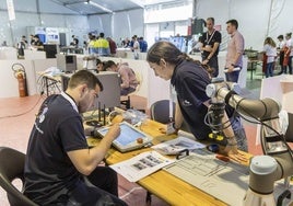 Dos alumnos de FP programan un brazo robot.