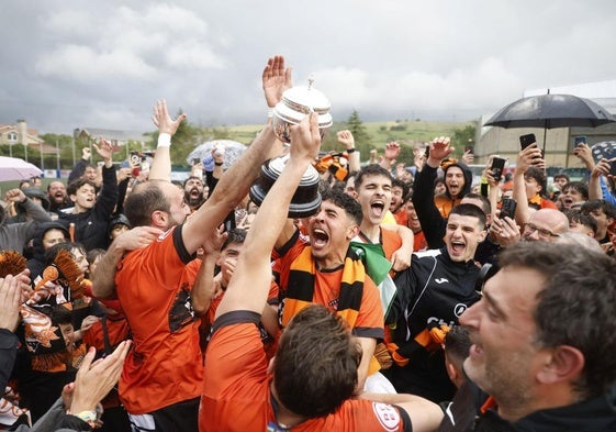Los jugadores del Sámano celebran el ascenso con sus aficionados sobre el mismo campo.