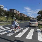 Una mujer cruza en bicicleta por la Avenida de la Constitución (S-20), una de las vías de acceso a Santander.