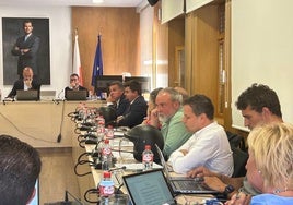Los grupos municipales PP y Vox con un casco de la Policía Local sobre la mesa del pleno.