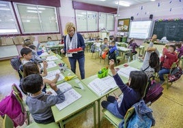 Una profesora de Cantabria reparte material a los alumnos durante una clase.
