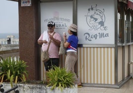 Dos personas se resguardan con sus helados durante la tormenta en El Sardinero.