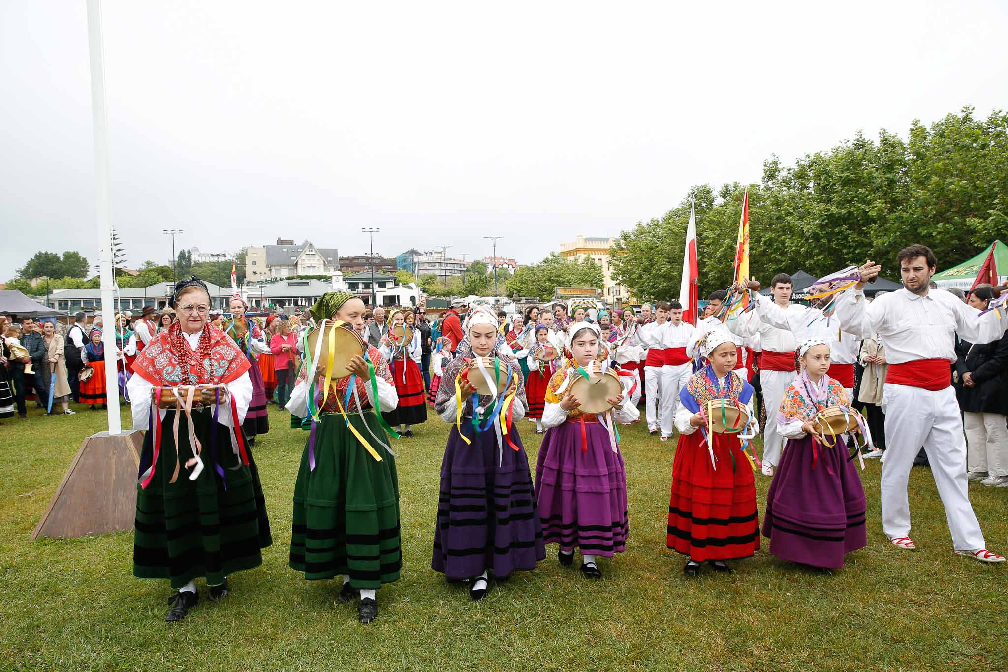 Varias generaciones de integrantes de la Agrupación Virgen de las Nieves de Tanos-Torrelavega tocan la pandereta.