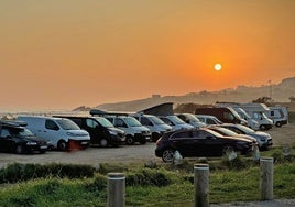 Varios coches estacionados en el aparcamiento de la playa de Oyambre.