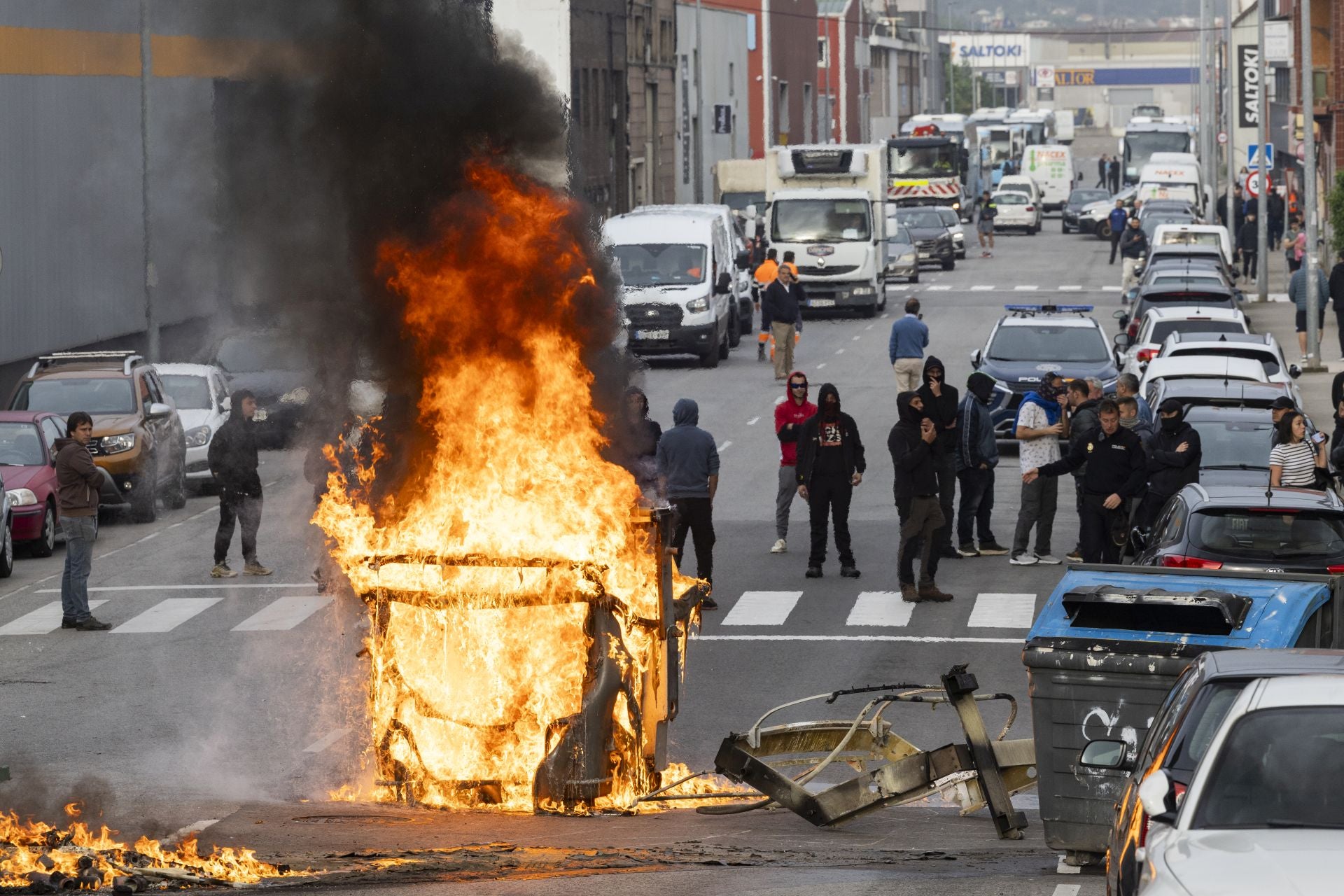 Huelguistas encapuchados ante el contenedor que quemaron en la entrada del polígono de Candina