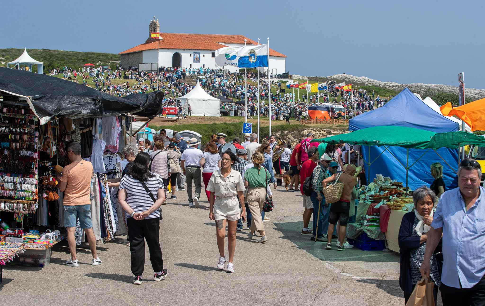 Los puestos del mercadillo, con las banderas y la ermita de fondo. 