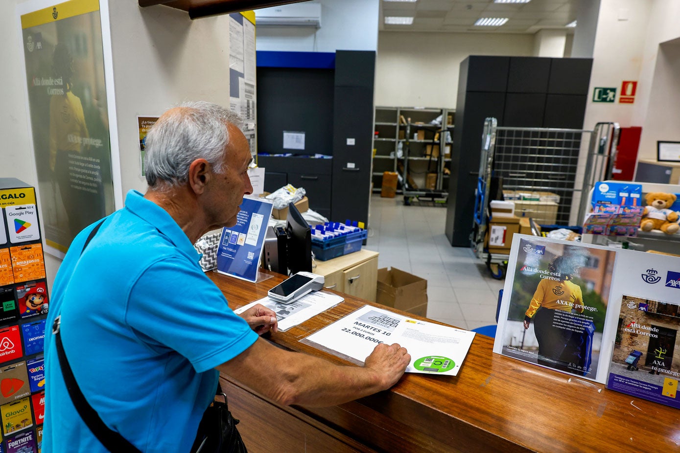 Un vecino de Torrelavega adquiere una etiqueta ambiental en las oficinas de Correos.