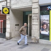 Un hombre pasea ante una oficina de Caixa.