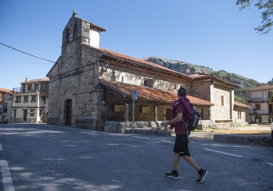 Un hombre pasea por la zona de la iglesia y la bolera de San Roque de Riomiera.