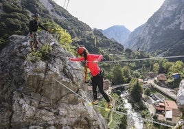Una mujer cruza un puente tibetano, uno de los pasos más famosos de la vía ferrata de La Hermida, en el municipio de Peñarrubia.