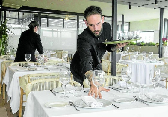 Profesionales de hostelería preparando un comedor para el servicio.