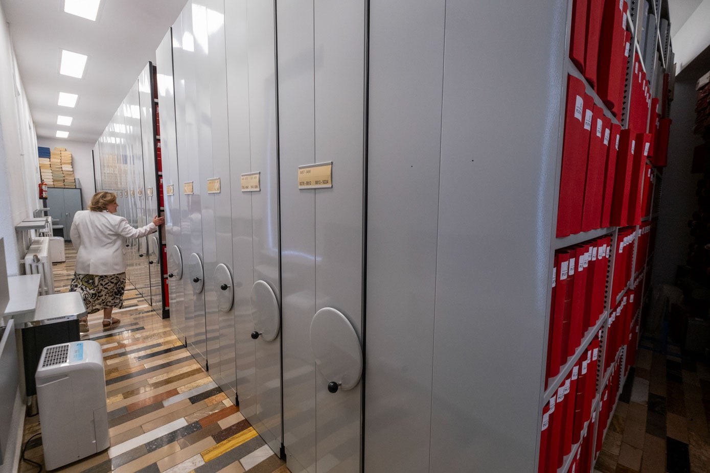 La archivera, Carmen López, mueve una de las grandes estanterías que albergan 2.340 metros lineales de documentación.