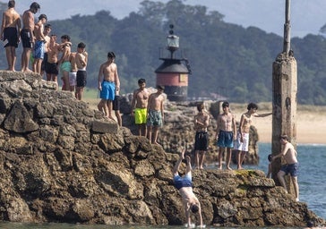 Varios jóvenes hacen cola, ayer, sobe el espigón de la playa de Bikinis, en Santander