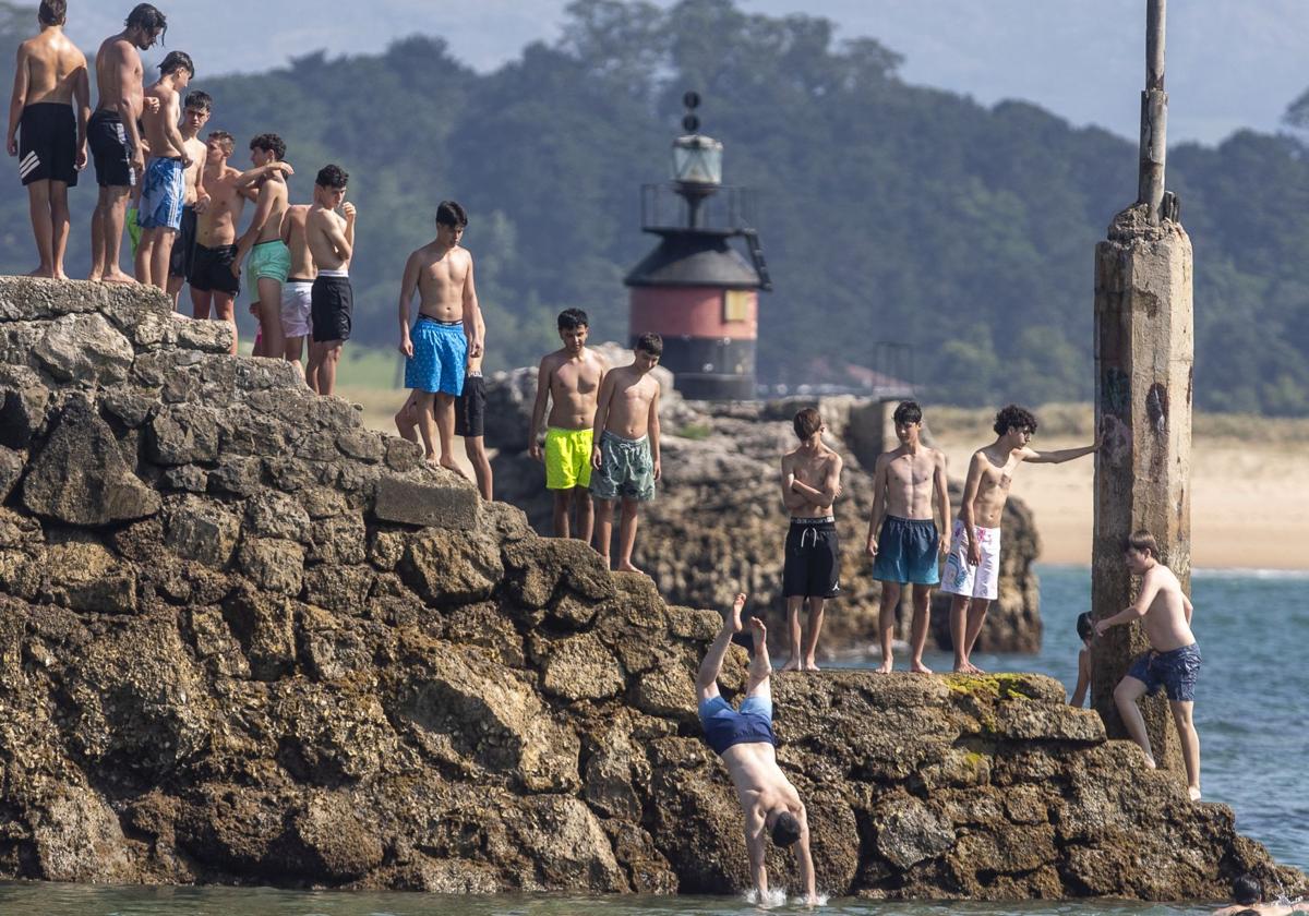 Varios jóvenes hacen cola, ayer, sobe el espigón de la playa de Bikinis, en Santander