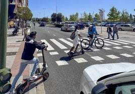 Varios usuarios de patinetes y bicicletas cruzan por un paso de peatones de Marqués de la Hermida.