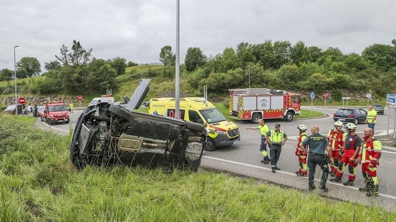 El coche volcado en el lugar del accidente junto a agentes de la Guardia Civil, 061 y Bomberos.