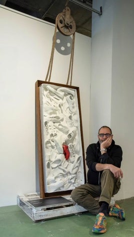 El artista Juanma Tapia juntos a su obra «Carnemigrante, por cuartos o enteros»