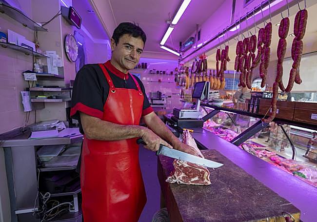 Foro Cagigas parte una chuleta frente al mostrador de su carnicería.