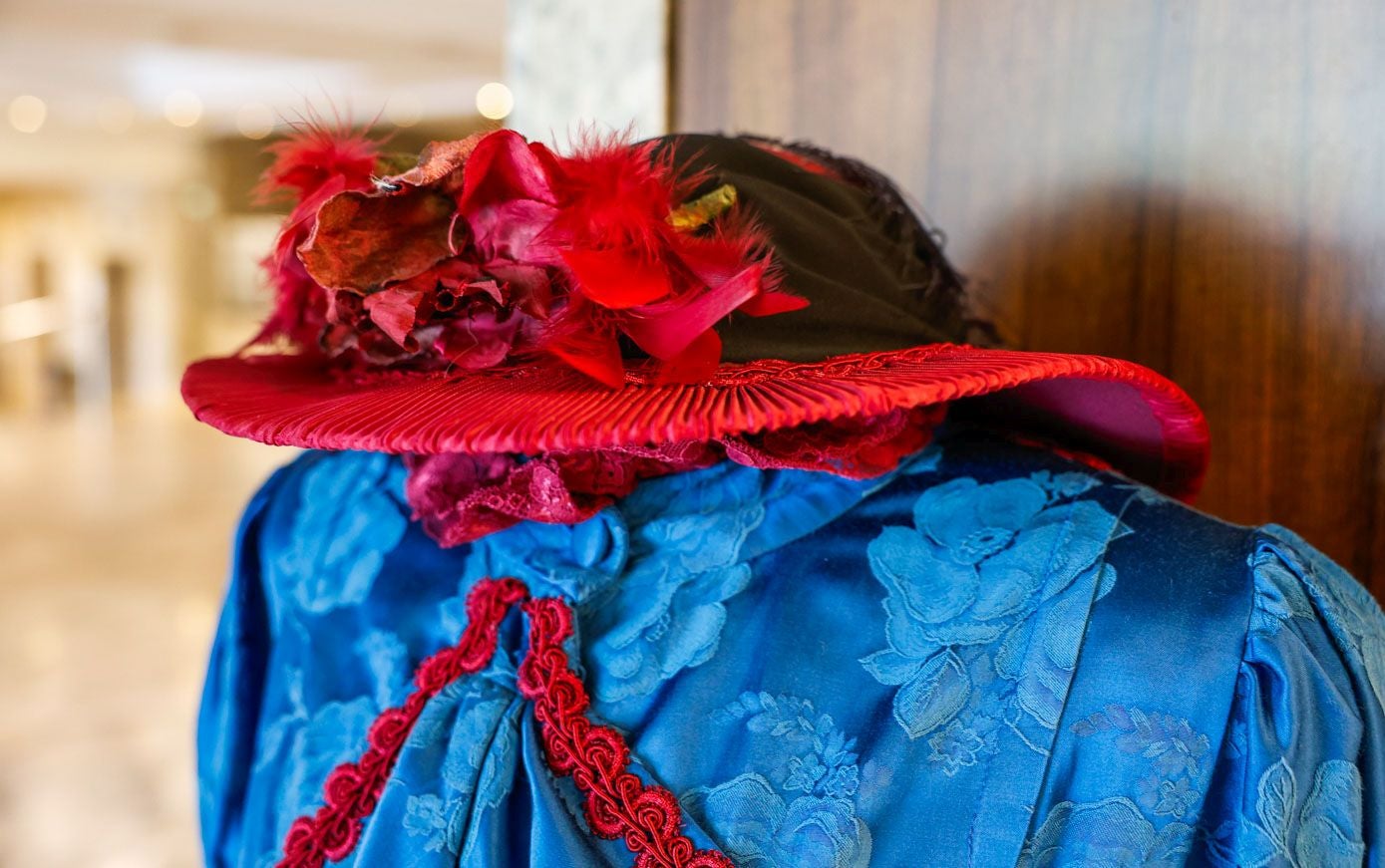Sombrero forrado con tela plisada roja y flores como adorno principal.