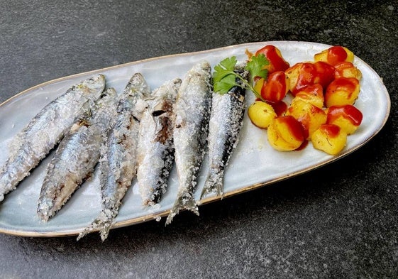 Las sardinas a la sal, preparadas para disfrutarlas, con unas patatas con salsa picante.