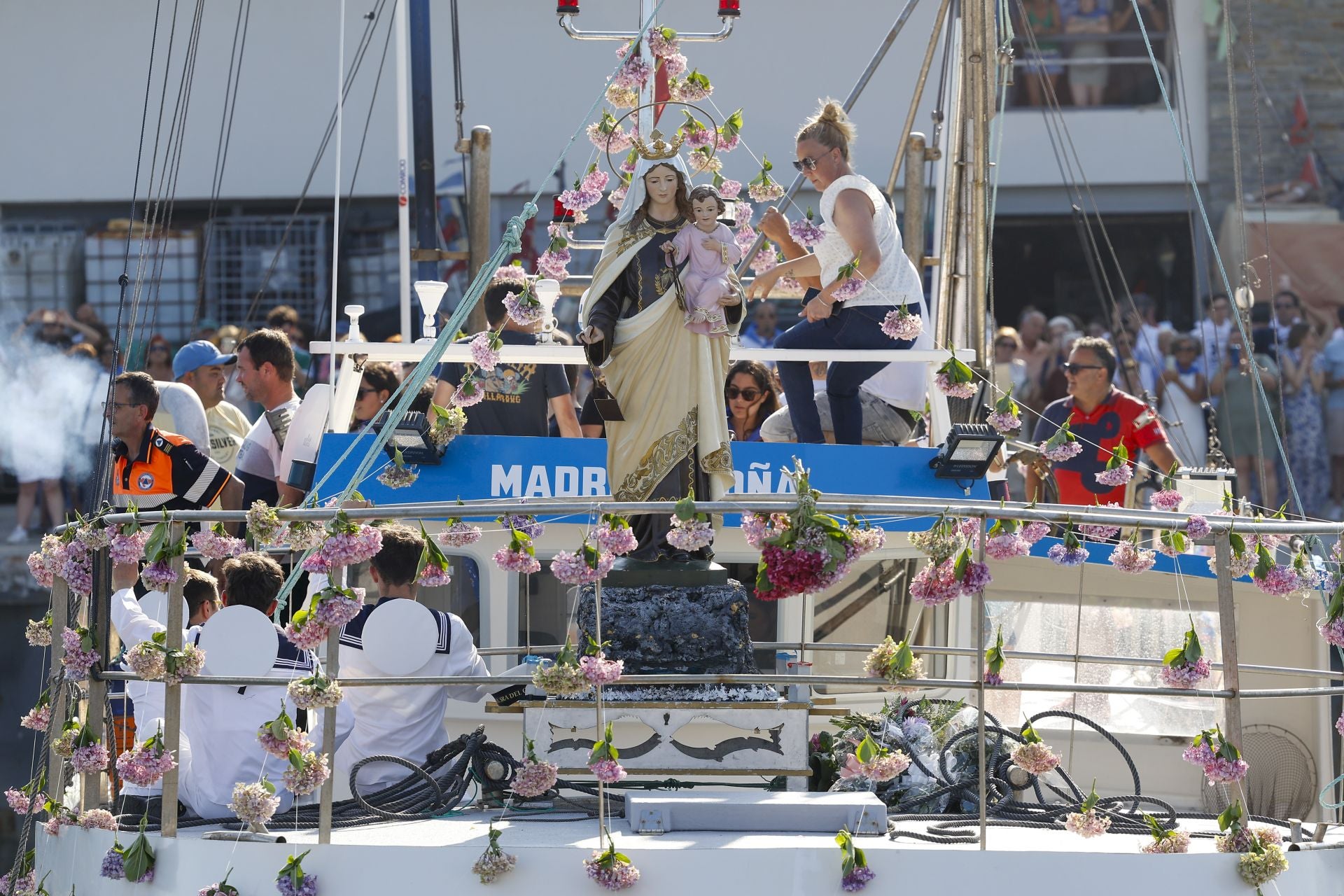La imagen de la Virgen y el niño, en primer término, en el barco, adornado con flores.