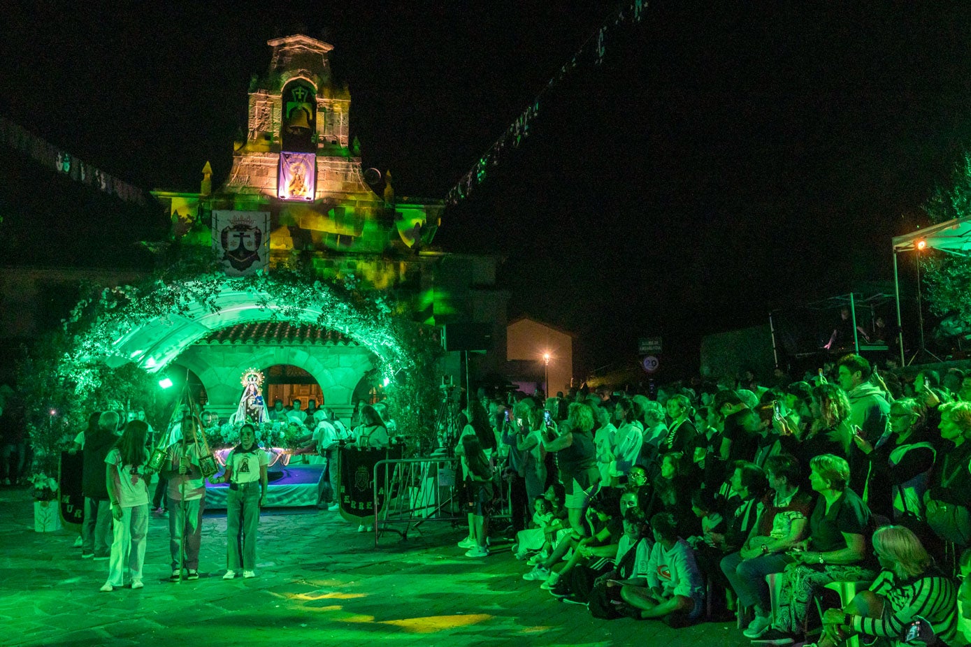 La Virgen del Carmen, con sus mejores galas y sobre una barca, preside la primera misa de la mañana en la puerta del templo en Revilla.