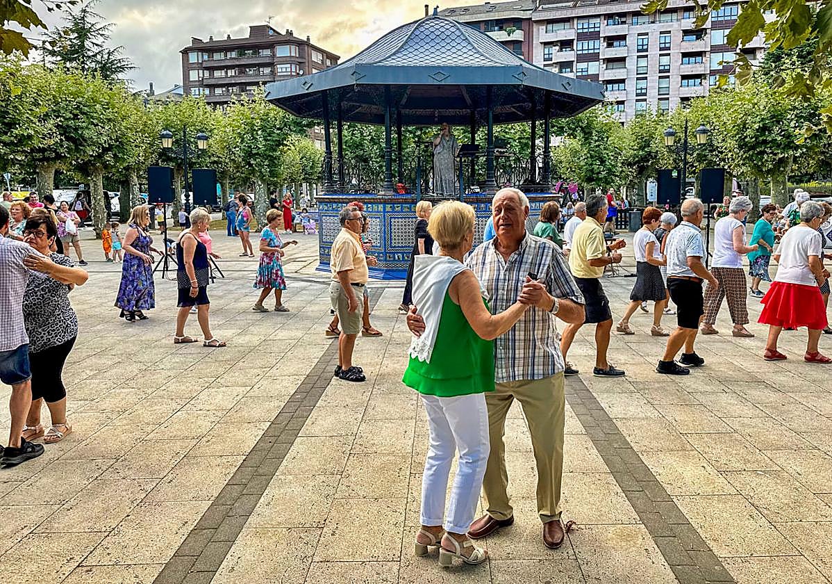 Las parejas de mayores bailan en el entorno del kiosco de Colindres, en el que canta Rosana Garín.