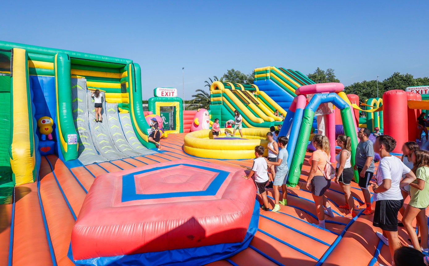 Niños y jóvenes hacen fila para lanzarse por los toboganes y escalar los hinchables