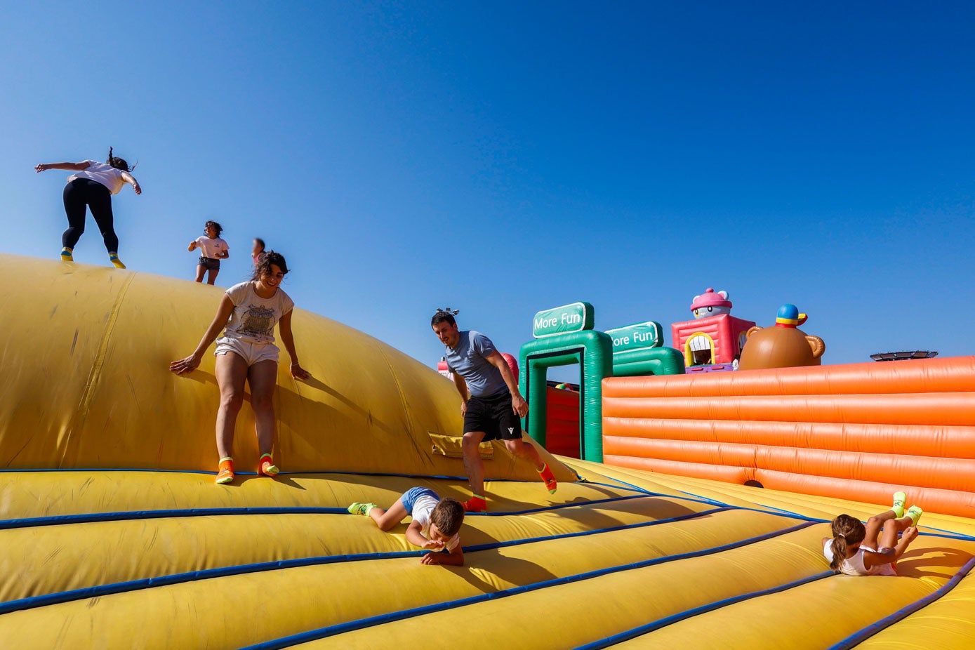 Pequeños y mayores trepan, corren y ruedan entre risas en una colina hinchable