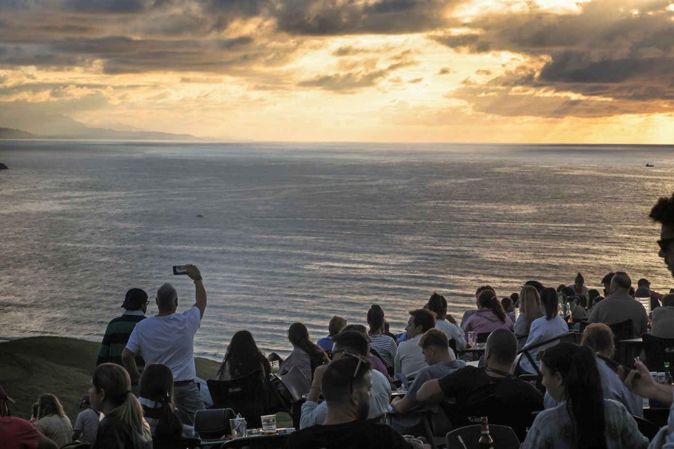 Las numerosas personas congregadas en El Rayo Verde contemplan con expectación el momento de la puesta del sol.