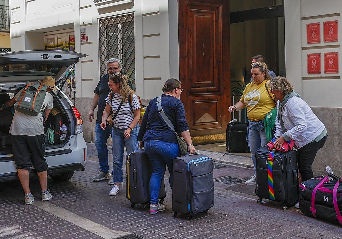 Un grupo de turistas carga con maletas a la entrada de una vivienda de uso turístico.