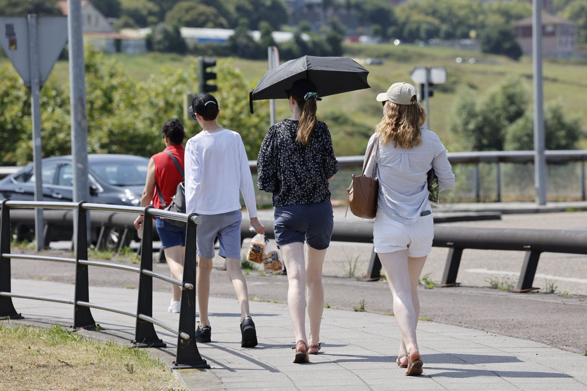 Protegidas del sol bajo un paraguas, un grupo de mujeres pasea por la S-20