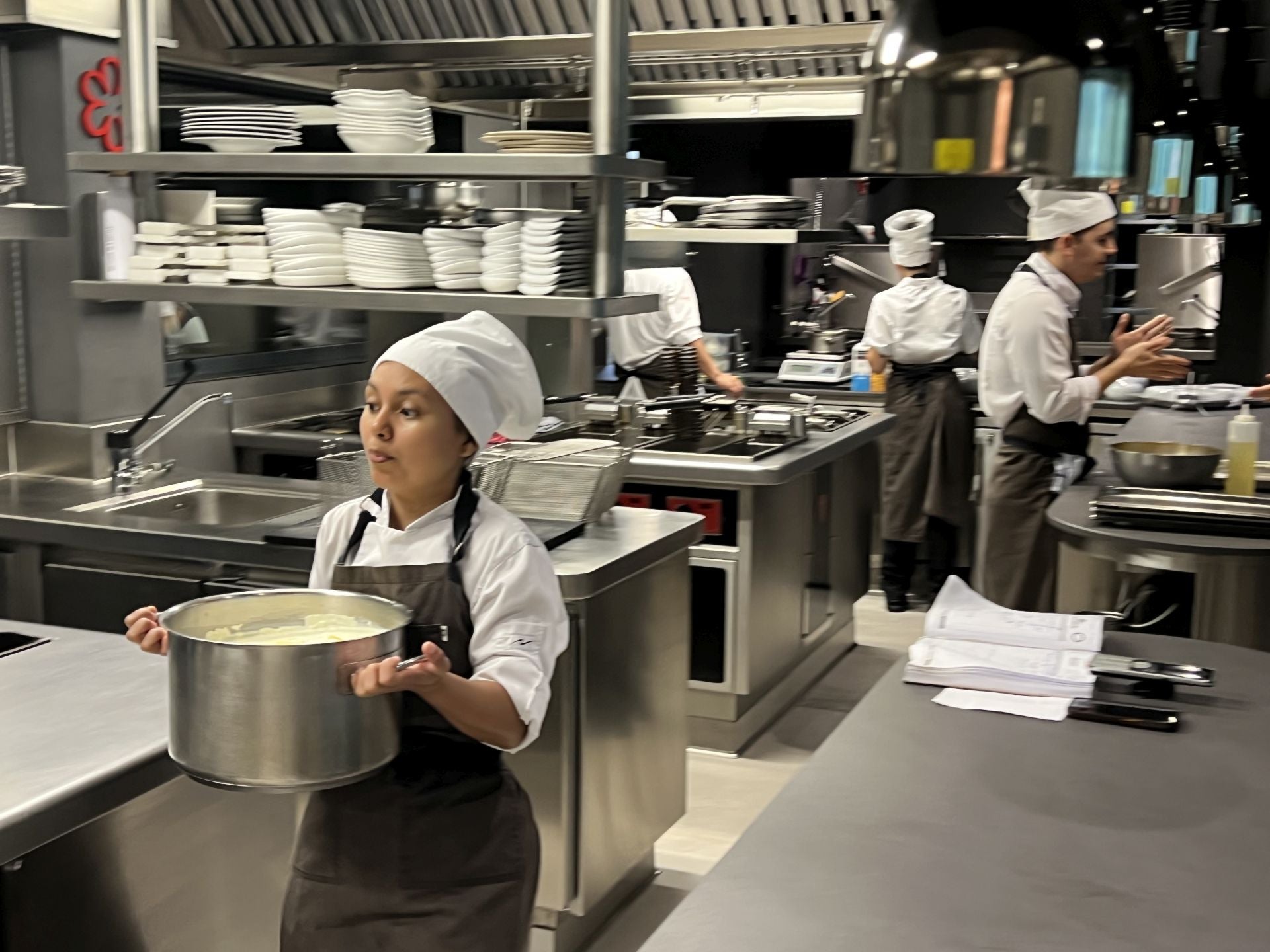 Keila, responsable de repostería en el cuarto frío, lleva una cazuela para poner en uno de los fuegos de la cocina.