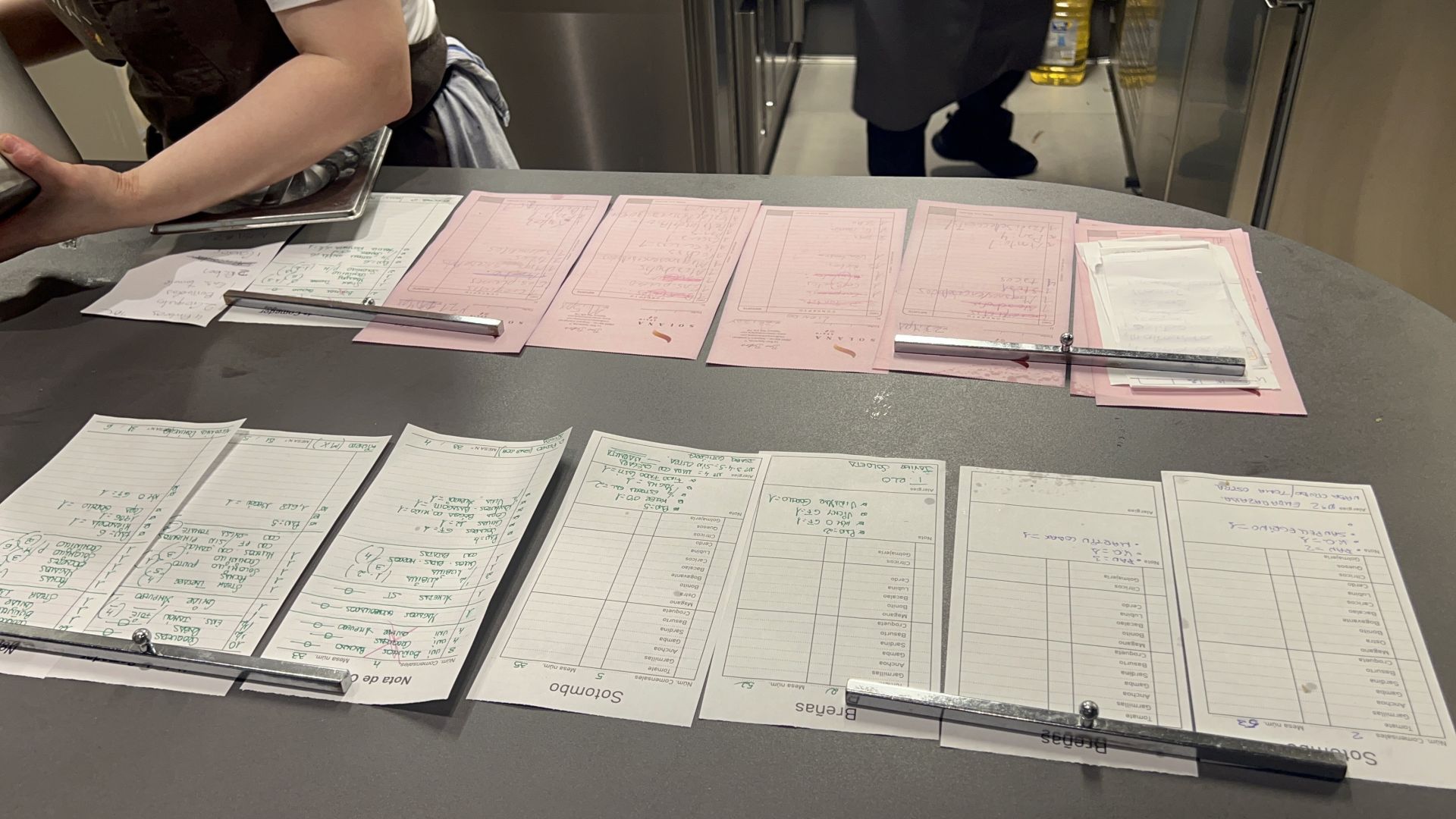 La intensidad del servicio lo delantan las comandas, en blanco las del restaurante gastronómico, en rosa, las del bar-taberna, y en notas más pequeñas, las de la terraza. Todo sale al mismo tiempo desde una única cocina.